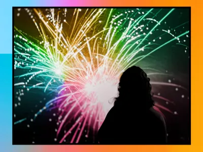 A silhouette of a person with curly hair is viewed from behind, looking towards a vibrant display of fireworks. The fireworks feature a spectrum of colors including green, pink, and yellow, with light trails against a dark background. The image is bordered with a color gradient that transitions from blue to orange, creating a frame around the scene.