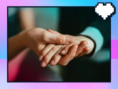 A close-up photo of two people gently holding hands, showcasing the palms and fingers interlocking with each other. The image has a heart-shaped icon in the upper right corner and is bordered by a pink frame.